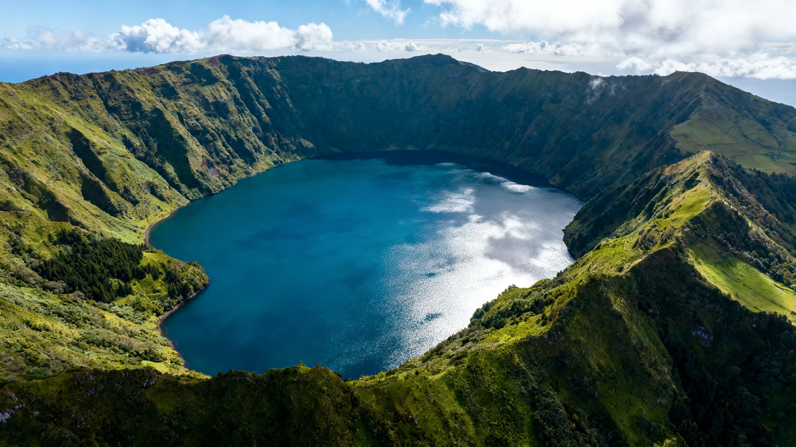 Aerial view of Lagoa do Fogo crater lake surrounded by green volcanic walls